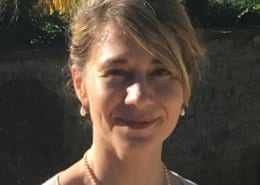 A person is outdoors, with a natural background of greenery and sunlight highlighting features. No recognizable landmarks or historical buildings are visible.