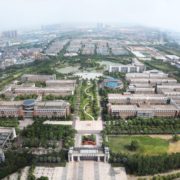 A bird's-eye view of an urban area reveals a residential suburb with a tree-lined sky, a house, buildings, mountains, and a cityscape, creating a stunning aerial landscape for travel.