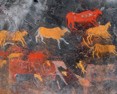 Ancient cave painting depicting red and orange cattle and human figures, showcasing early art and communication on a rock surface.
