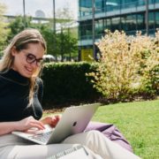 A person sits on the grass and uses a laptop.