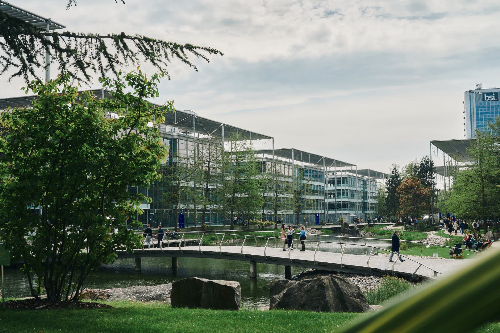 A city park showcases its lush greenery and unique architecture against a backdrop of fluffy clouds in the bright blue sky.