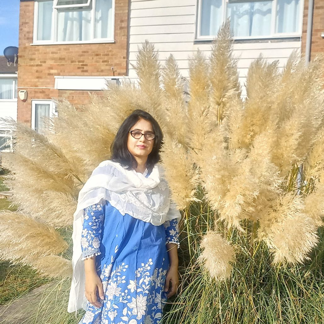A person stands in front of a building with a large cactus.