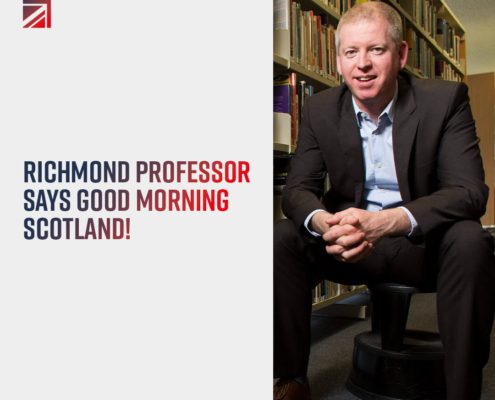 A person seated in a library, smiling at the camera, with text, "Richmond Professor says Good Morning Scotland!" and a website URL.