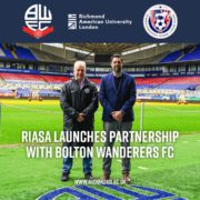 Two people stand in a stadium; text announces RIASA's partnership with Bolton Wanderers FC, alongside logos of the involved organizations.