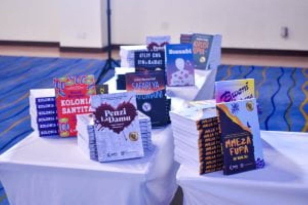 The image shows a display of stacked books on a covered table, presumably at a book fair or promotional event, with no people visible.