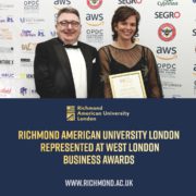Two people are posing with an award certificate at an event, likely a business awards ceremony, with multiple logos and event information in the background.