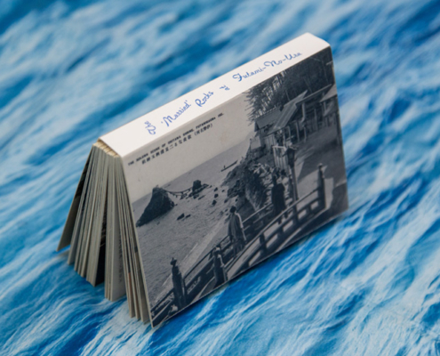 A flipbook with a black and white photo cover is placed on a blue surface with a wavy, water-like pattern.