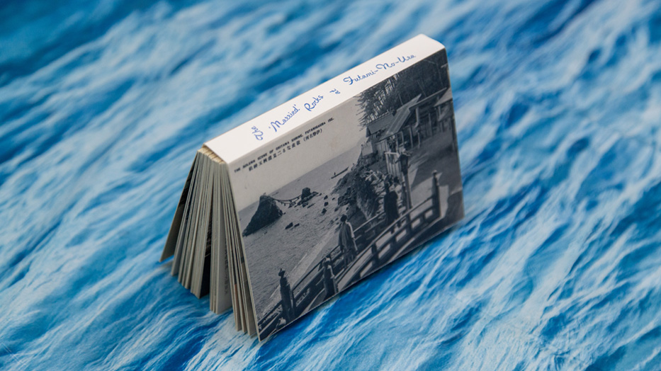 A flipbook with a black and white photo cover is placed on a blue surface with a wavy, water-like pattern.