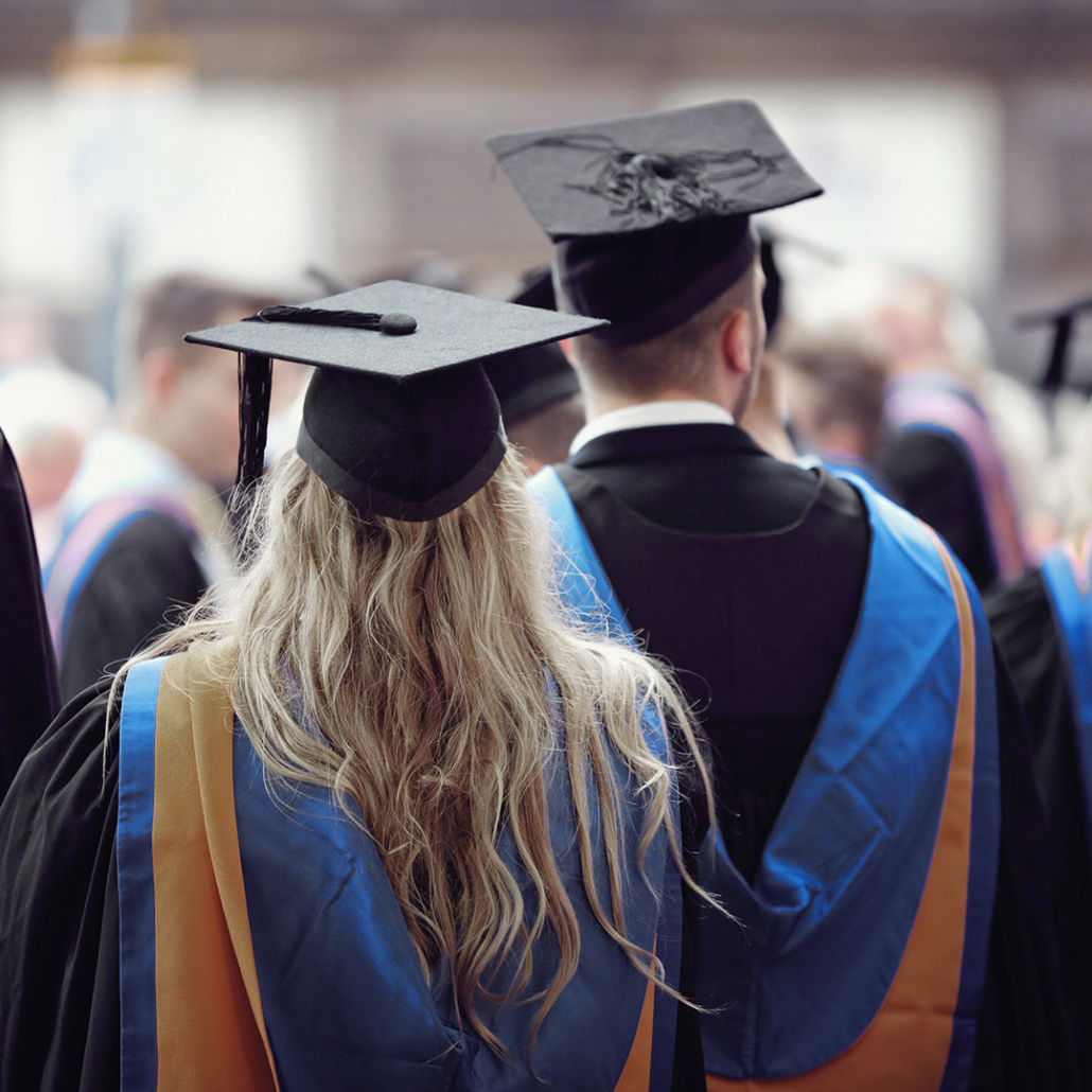 This image shows a group of graduates in caps and gowns during a commencement ceremony, depicting the celebration of academic achievements.