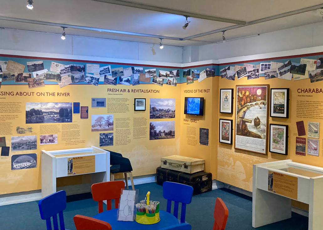 This image shows an educational display room with colorful walls, historical photographs, descriptive texts, and interactive exhibits for children.