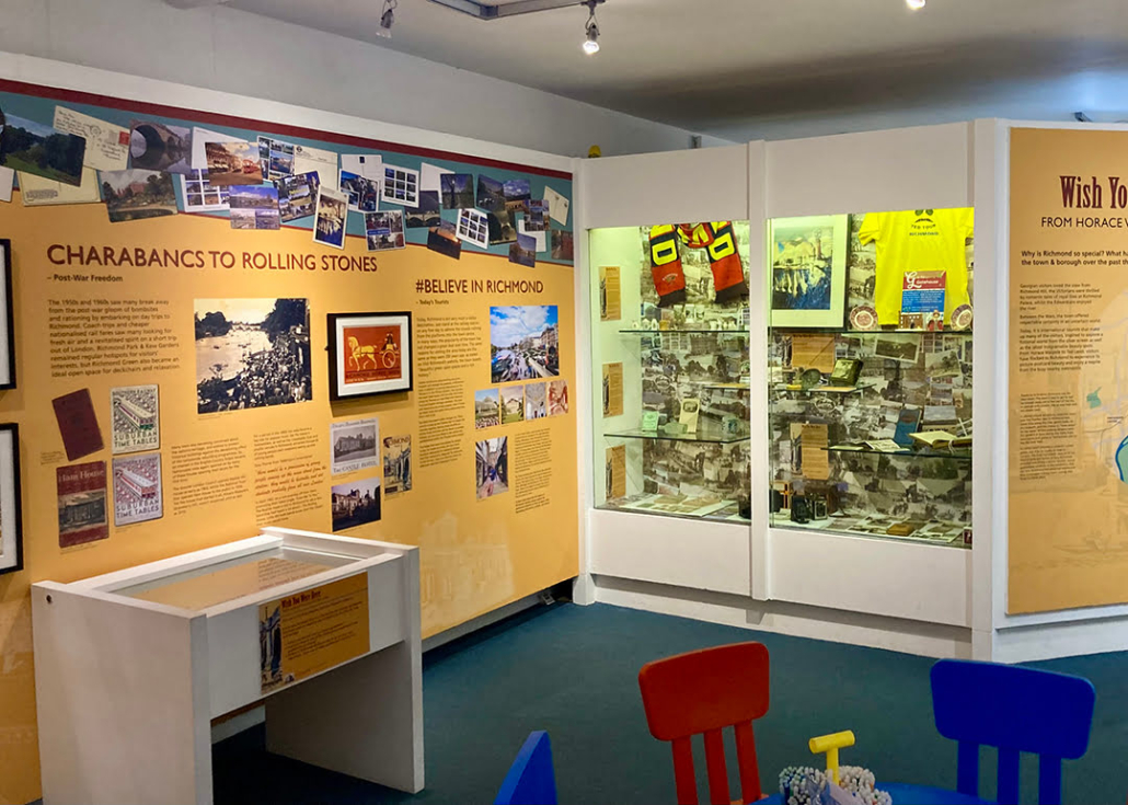 This is an interior view of a museum exhibit featuring colorful display panels with images and text, a glass display case, and a children's play area.