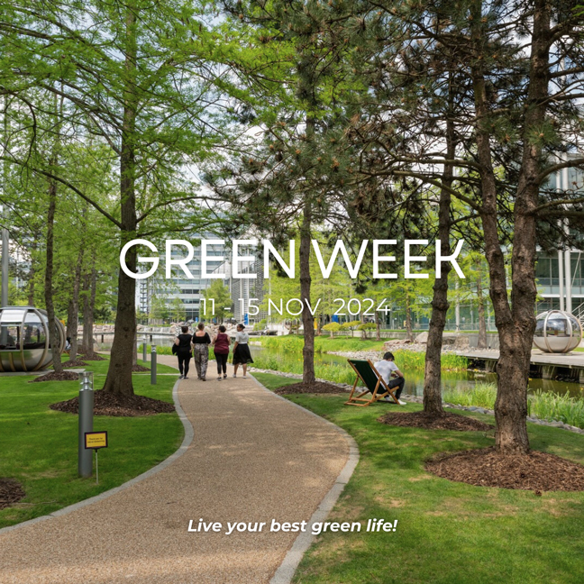 A park scene with people on a path, leafy trees, and small ponds; sign advertises "Green Week" event in November 2024.