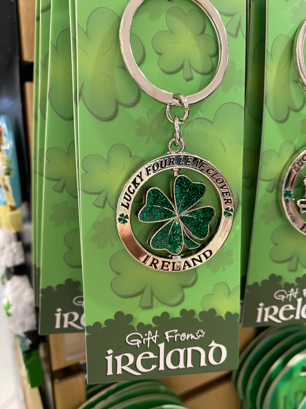 Green keychain featuring a glittery four-leaf clover with "Lucky Four Leaf Clover Ireland" text. Labeled "Gift from Ireland" on packaging.