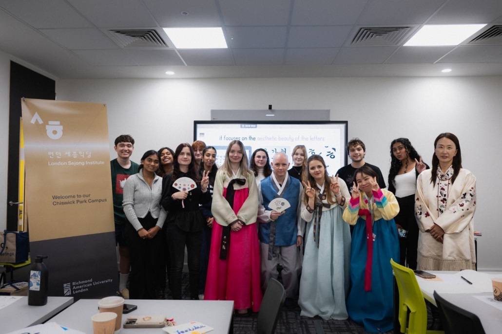 A group of people at the London Sejong Institute Chiswick Park Campus. Some wear traditional Korean attire, posing in a classroom setting.