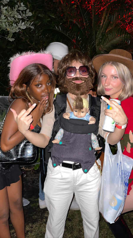 Three people in costumes, with one wearing a beard and sunglasses, posing outdoors at night. They hold humorous gestures and props.