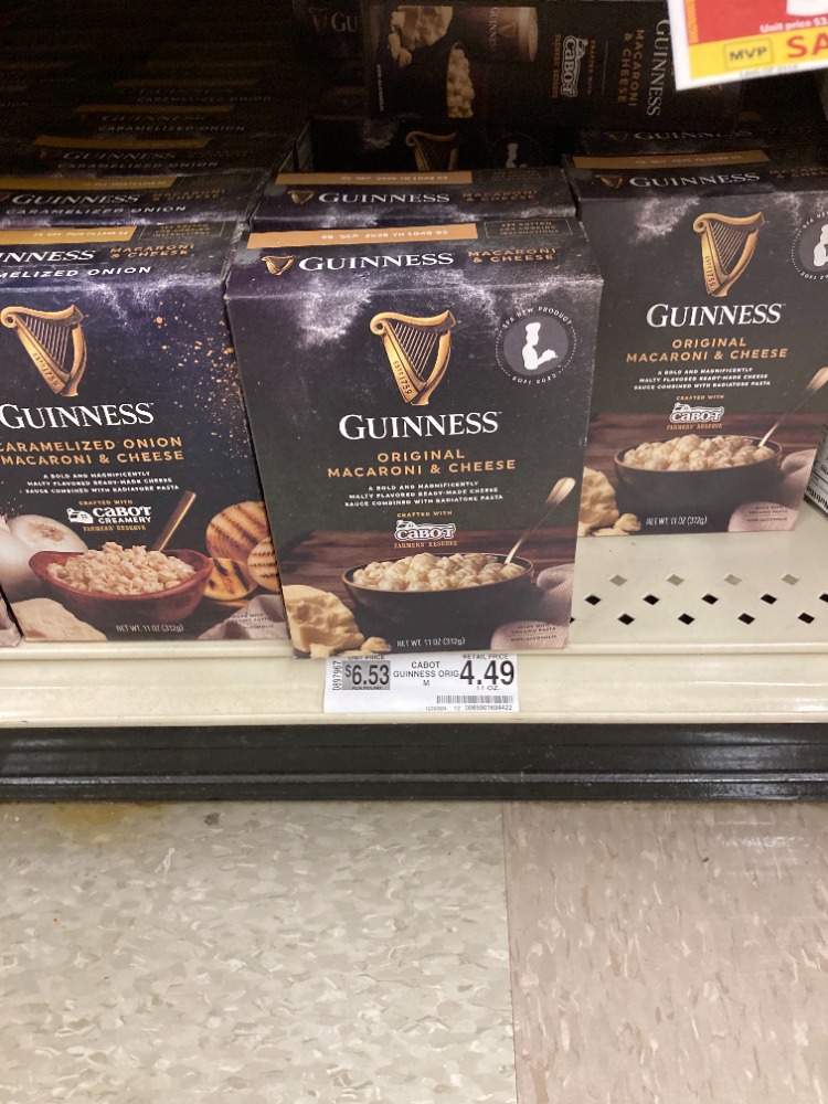 Boxes of Guinness Original Macaroni & Cheese are displayed on a grocery store shelf, priced at $4.49, featuring the iconic harp logo.