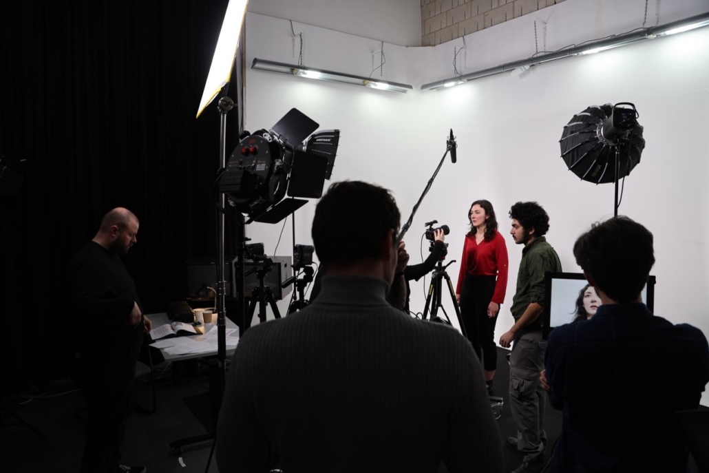 Several people in a studio with professional lighting and cameras, working on a filming or photography project.