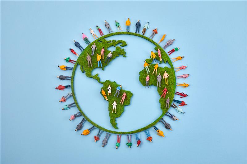 A globe with miniature, colored figures represents global diversity with people standing on continents against a blue background.