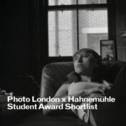A person lounges on a chair indoors, gazing upward. Brick building visible through window. Text: "Photo London x Hahnemühle Student Award Shortlist."