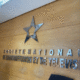 A metallic star logo and French text, "Société Nationale de Radiodiffusion et de Télévision," appear on a wooden wall in an office setting.