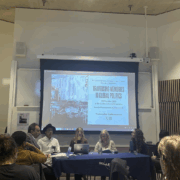 A panel of six people discusses at a conference table, under a projected screen at the London School of Economics event.