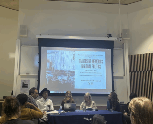 A panel of six people discusses at a conference table, under a projected screen at the London School of Economics event.