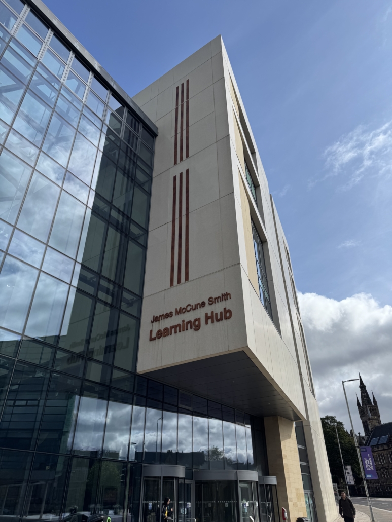 The image shows the James McCune Smith Learning Hub with a person walking. The University of Glasgow's tower is visible in the background.