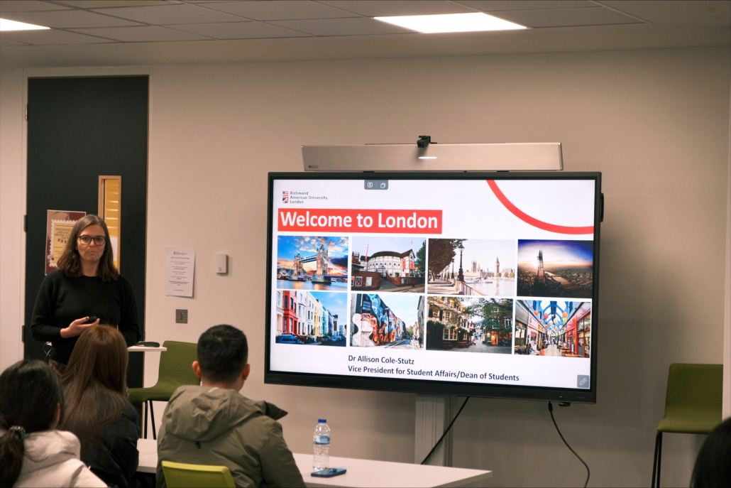A person presents to a group with a screen displaying "Welcome to London," featuring images of landmarks like Tower Bridge.